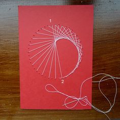 a piece of red paper with white thread on it