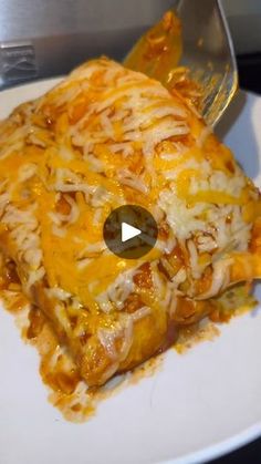 a white plate topped with lasagna covered in cheese and sauce next to a fork