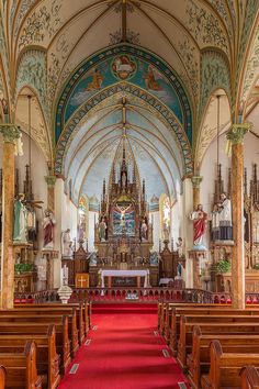 the inside of a church with red carpet and wooden pews