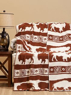 a brown and white blanket sitting on top of a wooden table next to a lamp