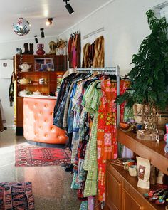 a room filled with lots of clothes and furniture next to a plant in a vase