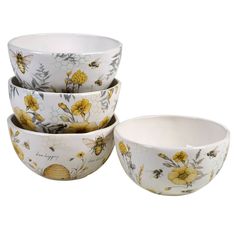 four white bowls with yellow flowers and bees on them, all stacked up in front of each other