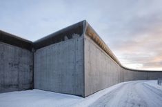 an empty concrete building with snow on the ground and sky in the backround