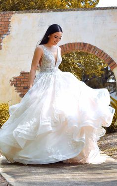 a woman in a wedding dress is walking down the street with her hand on her hip