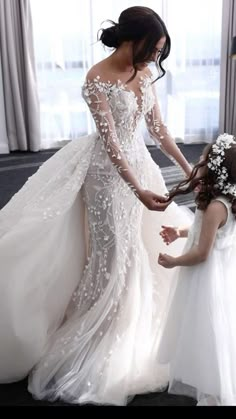 two women in wedding dresses standing next to each other and one is holding the hand of another woman