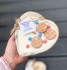 a person holding up a small waffles and biscuits shaped cookie in front of them