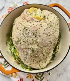 a pot filled with meat and vegetables on top of a marble countertop next to an orange handled spatula