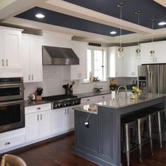 a large kitchen with white cabinets and stainless steel appliances, along with dark wood flooring