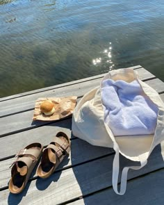 a pair of shoes sitting on top of a wooden dock next to a white bag