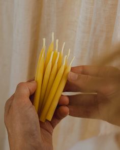 a person holding some yellow candles in their hand