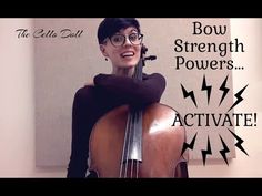 a woman with glasses holding a cello in front of a sign that says bow strength powers activate