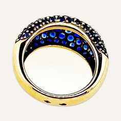 a gold ring with blue and black stones on the inside, set against a white background