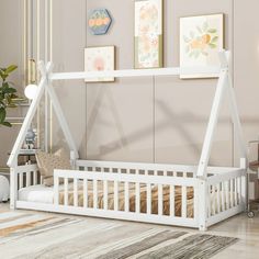 a white wooden bed frame in a living room with pictures on the wall above it