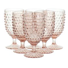 four pink glass goblets are lined up in a row