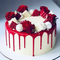 a white cake with red and white decorations on it's top, sitting on a plate