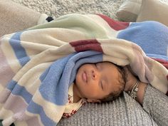 a baby wrapped in a blanket is laying on the floor with his head tucked under a blanket