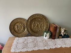 two decorative plates sitting on top of a wooden table next to a lace doily