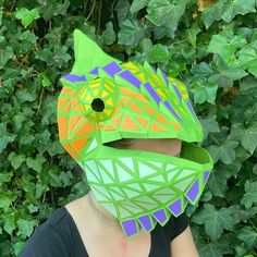 a woman wearing a green and orange mask with an animal design on it's face