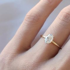 a woman's hand with a diamond ring on top of her finger, showing the center stone