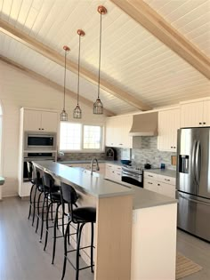 a kitchen with an island and several stools in front of the counter top area