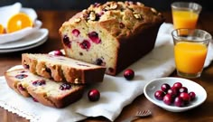 a loaf of cranberry orange bread on a table with fresh fruit and juice