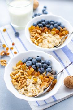 two bowls filled with oatmeal and blueberries next to a glass of milk