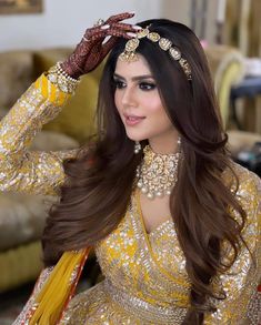 a woman in a yellow outfit with long hair and jewelry on her head, wearing a gold