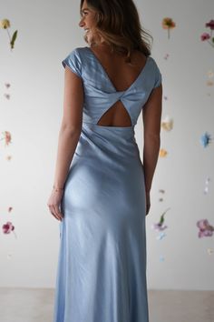 a woman in a blue dress looking back at the wall with flowers all over it