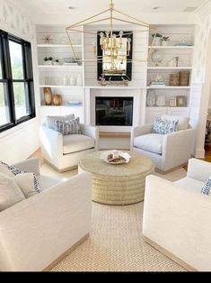 a living room filled with white furniture and a chandelier hanging from the ceiling