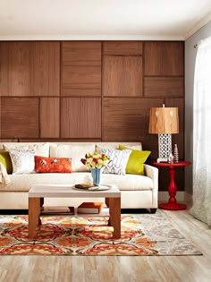 a living room with wood paneling and white couch, coffee table, lamps, and rugs