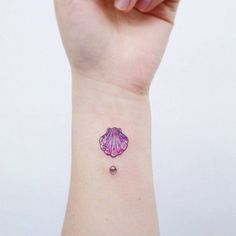 a small tattoo on the wrist of a woman's hand with a pink flower