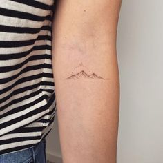 a woman's arm with a small mountain tattoo on the left side of her arm