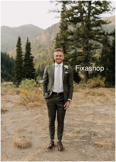 a man wearing a suit and tie standing in the middle of a field with trees