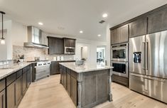 a large kitchen with stainless steel appliances and wood flooring is pictured in this image