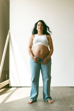 a pregnant woman standing in front of a white wall