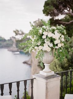 a vase filled with white flowers sitting on top of a balcony