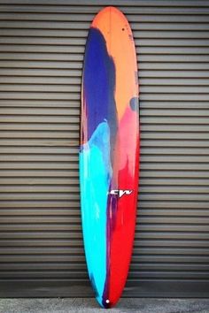 a colorful surfboard leaning against a garage door