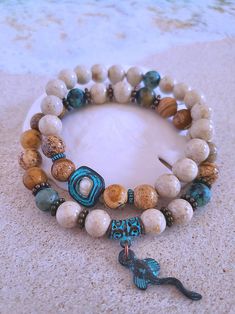 Get those sandy vibes flowing with our Beachy Bracelets, featuring natural stones, patina green accents, pearls, and cute ocean-inspired charms. Our Mykonos Collection would not be complete without some versatile, easy-to-use stretch bracelets. Wear one alone or stack a few for a bold BoHo look. Each bracelet features antiqued patina charms and spacers made in Greece, where the art of metal finishing was popular already thousands of years ago. Pearls, stingrays, shells, and other fun shapes ador Bohemian Beige Bracelets For Vacation, Bohemian Beige Bracelet For Vacation, Beige Bohemian Bracelets For Vacation, Bohemian Beige Jewelry For Meditation, Green Bracelets With 8mm Beads For Beach, Earthy Natural Stone Beaded Bracelets For Beach, Bracelets Pearls, Beachy Bracelets, Patina Green