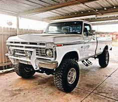 a white truck parked in a garage next to a wooden fence and metal roofing