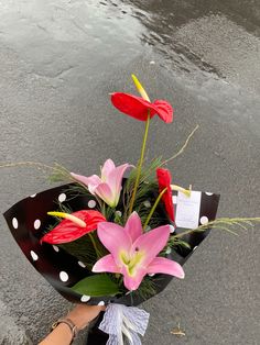 a woman holding a bouquet of flowers on the street with raindrops in the background