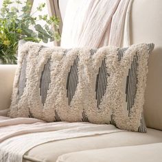 a white couch with two pillows on top of it next to a potted plant