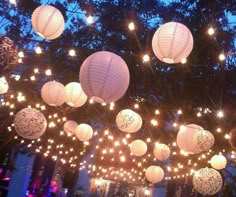 many paper lanterns are hanging from the ceiling in front of a building with lights on it