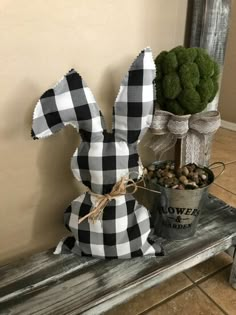 a potted plant sitting on top of a wooden bench next to a fake bunny