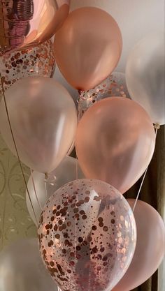 some pink and white balloons are hanging from the ceiling with gold confetti on them