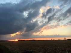 the sun is setting over an open field