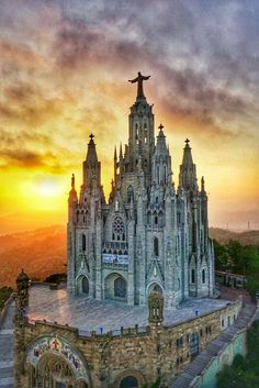 an aerial view of a cathedral with the sun setting in the background and clouds above it