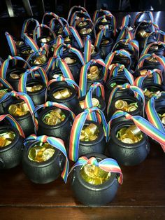 there are many small black pots with gold coins in them and ribbons on the sides