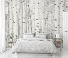 a white bed sitting under a wallpaper covered in trees