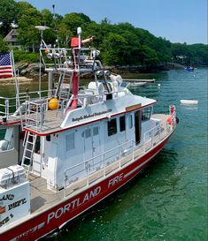 a red and white boat in the water with an american flag on it's side