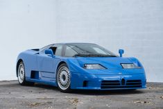 a blue sports car parked in front of a white wall